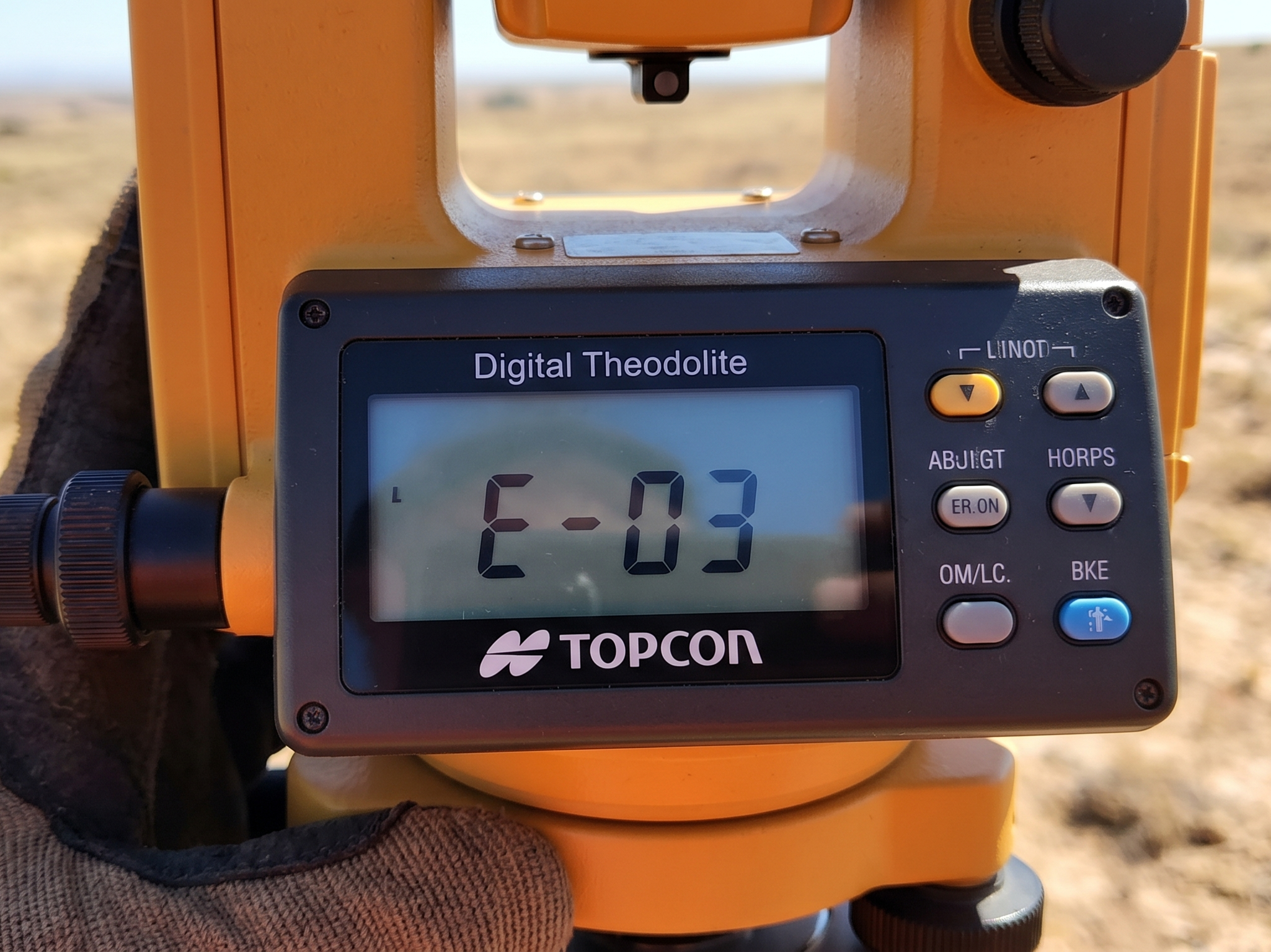 Close-up layar LCD Digital Theodolite (Topcon) menampilkan kode kesalahan 'E-03'